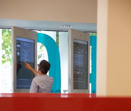 Bild zeigt Person, die vor einer elektronischen Anzeigetafel steht