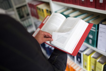 Bild zeigt jemanden der in einem offenen Buch blättert Bild zeigt jemanden der in einem offenen Buch blättert